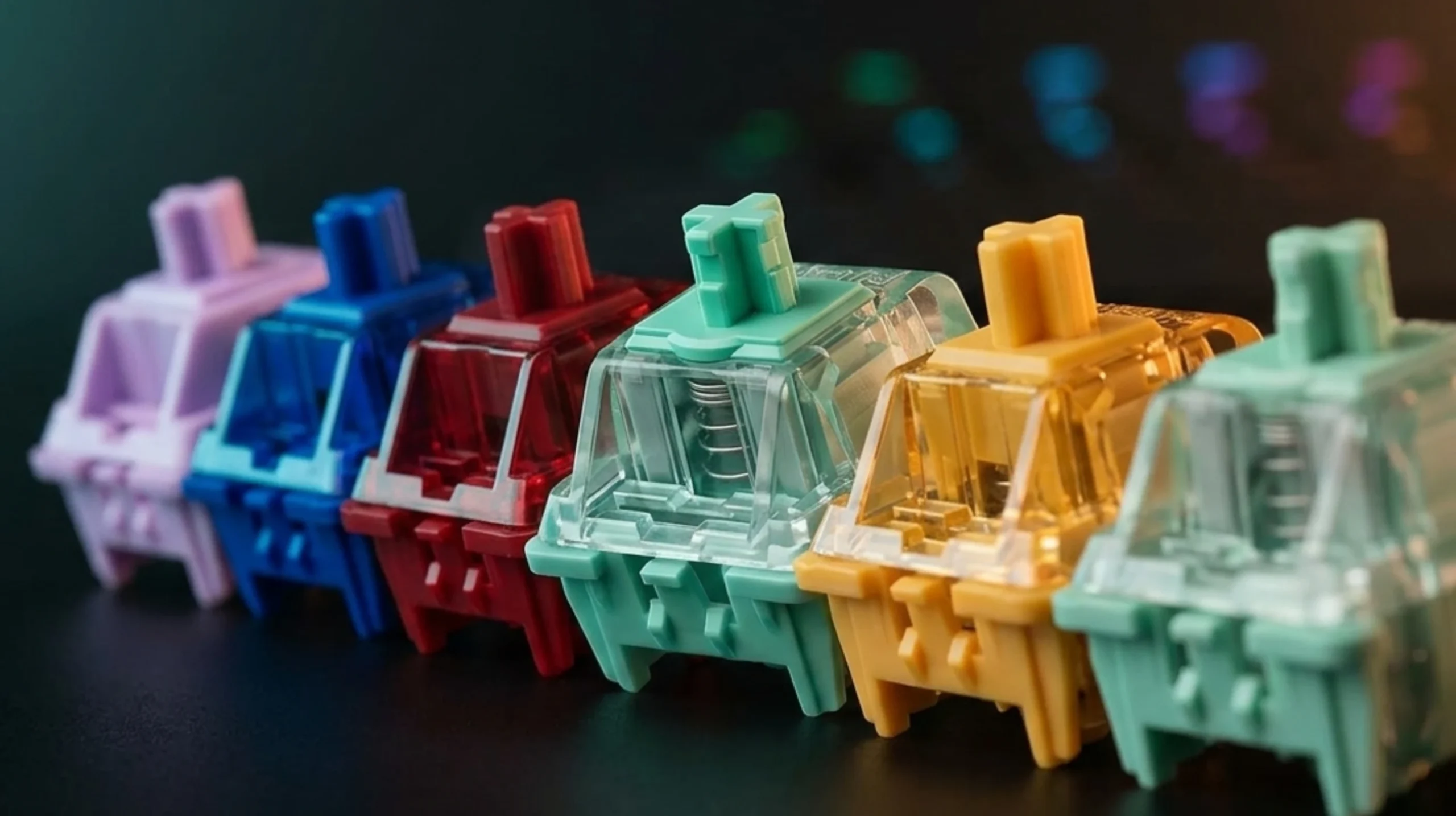 Row of mechanical keyboard switches in yellow, red, blue, purple, and jade green showing the best switches for gaming.